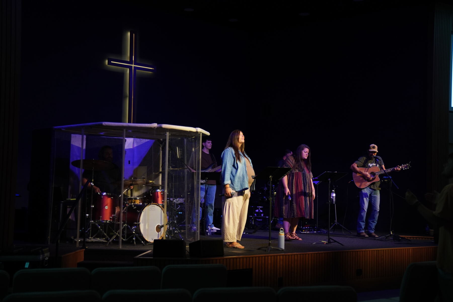 The band on stage beneath the glowing cross